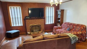 A living room with a leather sofa, a fireplace, a television, and a bookshelf. - Cozy & Convenient - 20 Minutes to Charleston WV (Elkview)