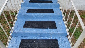 A set of blue-painted stairs leading to a door with a number plate, flanked by white railings and a brick wall. - Cozy & Convenient - 20 Minutes to Charleston WV (Elkview)