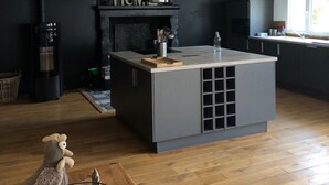 Une cuisine moderne dotée d’un îlot central, de meubles de couleur noire et d’une hotte de cuisson en acier inoxydable.
