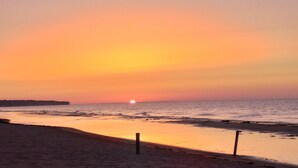 Une plage au coucher du soleil, avec une mer calme et un ciel dégagé.