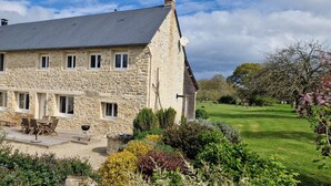 Une maison en pierre dotée d’un patio, d’un espace salon extérieur et d’un jardin bien entretenu.