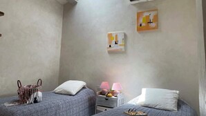 A bedroom with two beds, a skylight, an air conditioner, and two paintings on the wall. - Discount (already subtracted) of -40% (Lecci)