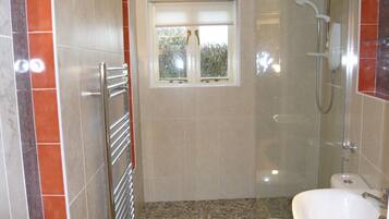 Een bad/douchecombinatie, handdoeken, zeep, toiletpapier