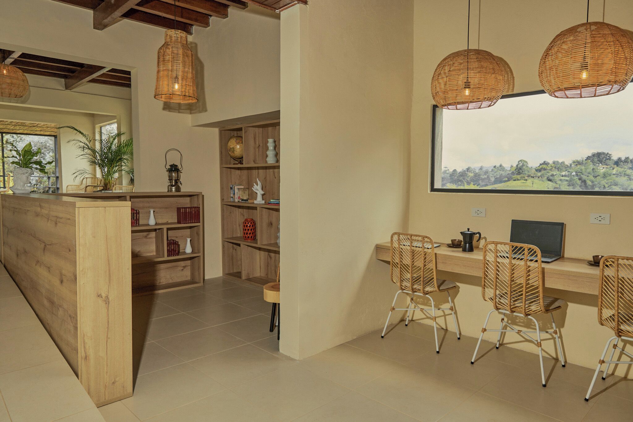 A modern kitchen with a wooden island, wicker chairs, and a large window overlooking a scenic landscape.