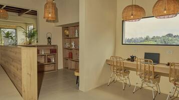 A modern kitchen with a wooden island, wicker chairs, and a large window overlooking a scenic landscape.