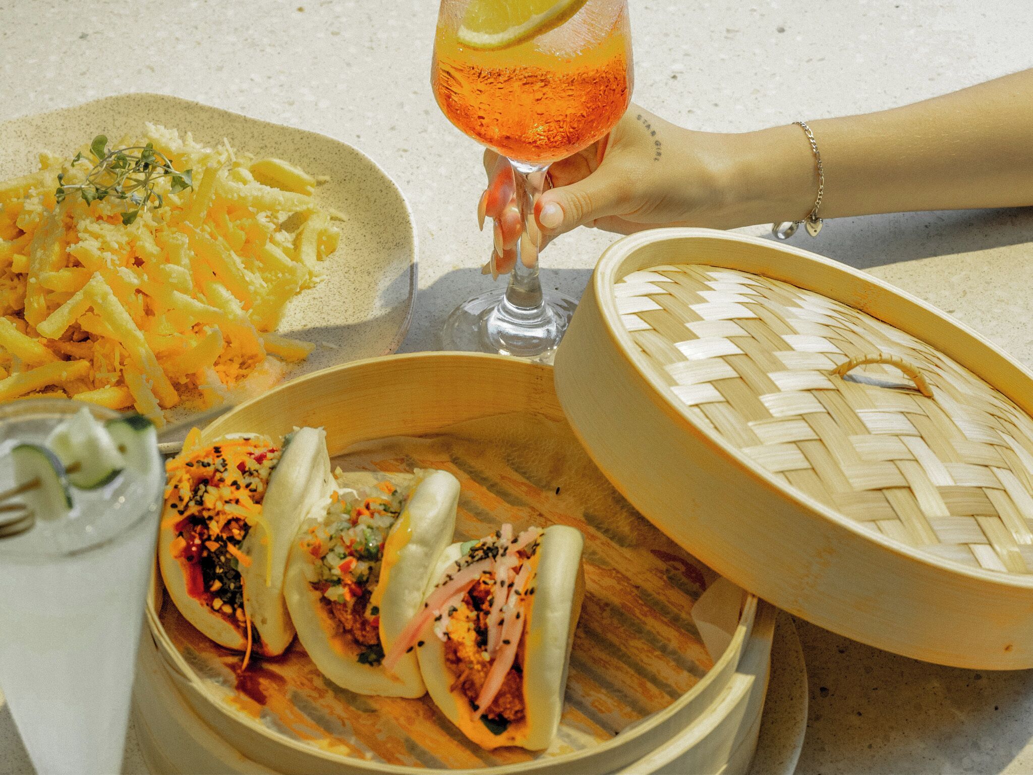 A table with a variety of dishes including a plate of shredded cheese, a bowl of soup, and a basket of dumplings.