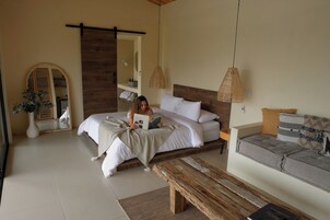 Un dormitorio con cama, mesita de noche y una zona de lectura con sofá y banco.