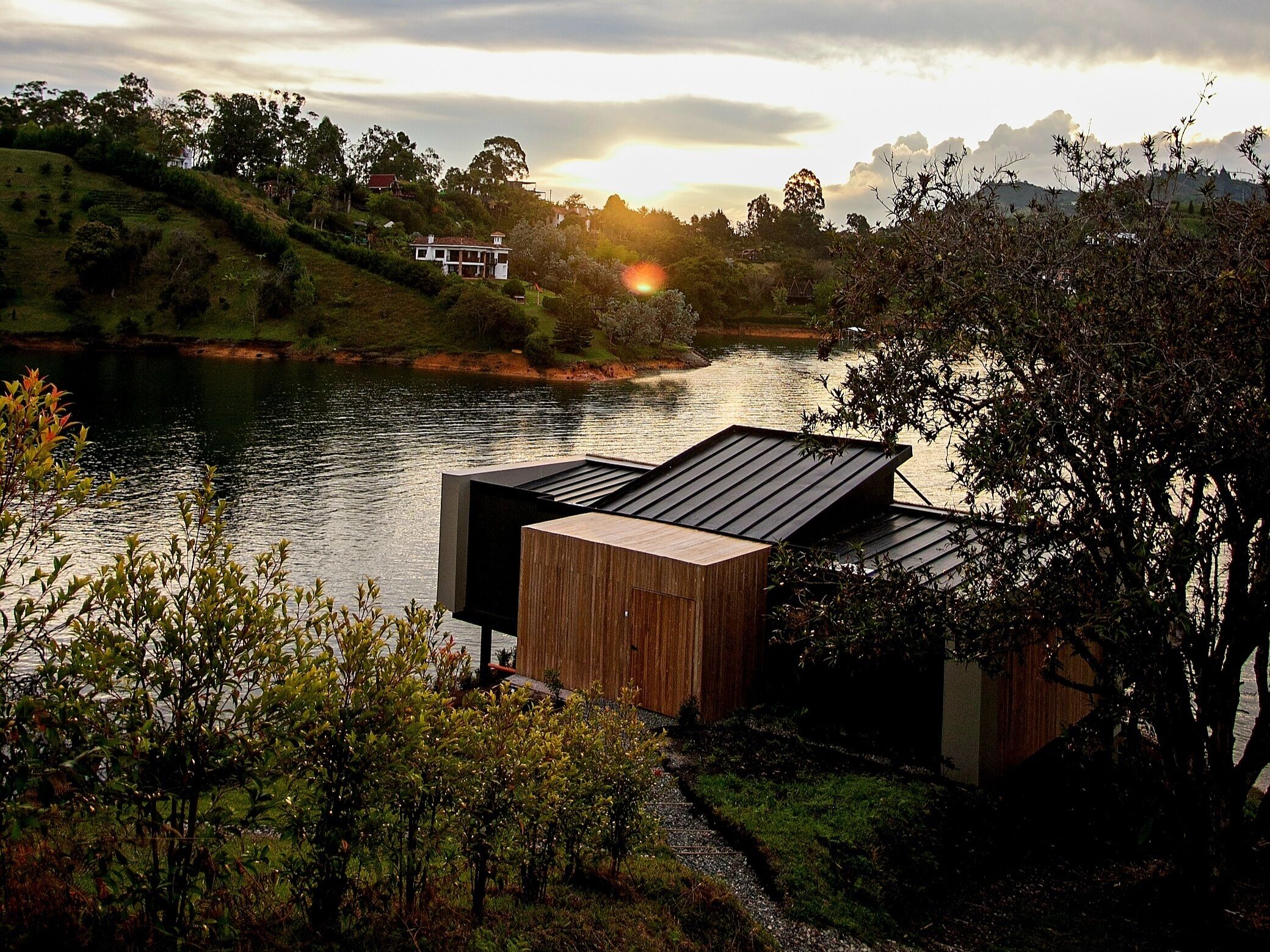 Una propiedad a la orilla del río con una terraza de madera y vistas al río y las colinas circundantes.
