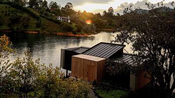 Una propiedad a la orilla del río con una terraza de madera y vistas al río y las colinas circundantes.