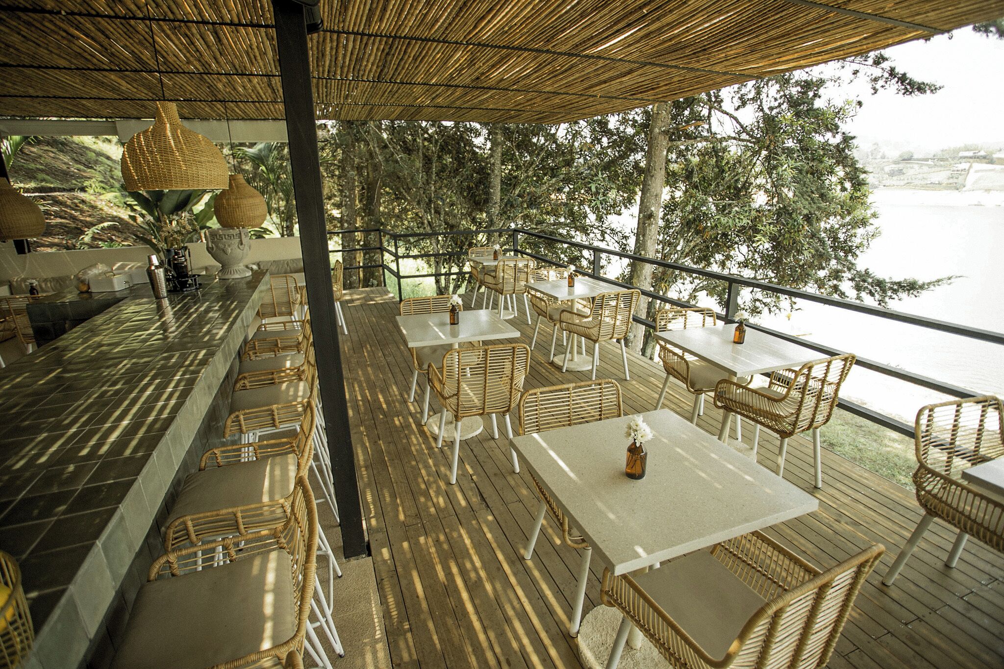 A covered outdoor dining area with wicker furniture and a view of a body of water.
