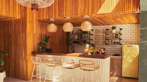 A modern kitchen with wooden accents, white bar stools, and a yellow refrigerator. - La Pausa Hotelbistro (El Peñol)