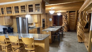 A kitchen with wooden cabinets, a granite countertop, and a central island with bar stools.