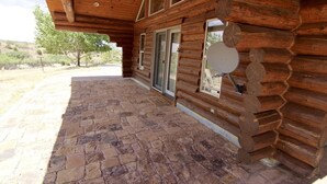 A log cabin with a stone-paved porch and large windows.