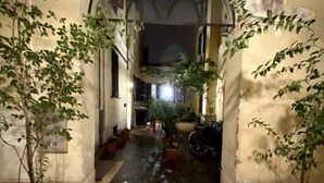 Une entrée en arc donnant sur une cour intérieure agrémentée de plantes en pot et d’un vélo.