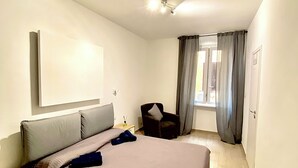 Une chambre d’hôtel avec un grand lit, une chaise, une table de chevet et une fenêtre avec des rideaux.
