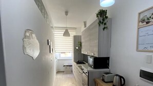 Une cuisine moderne avec un plan de travail en bois, un luminaire suspendu et une vue sur l’espace repas.