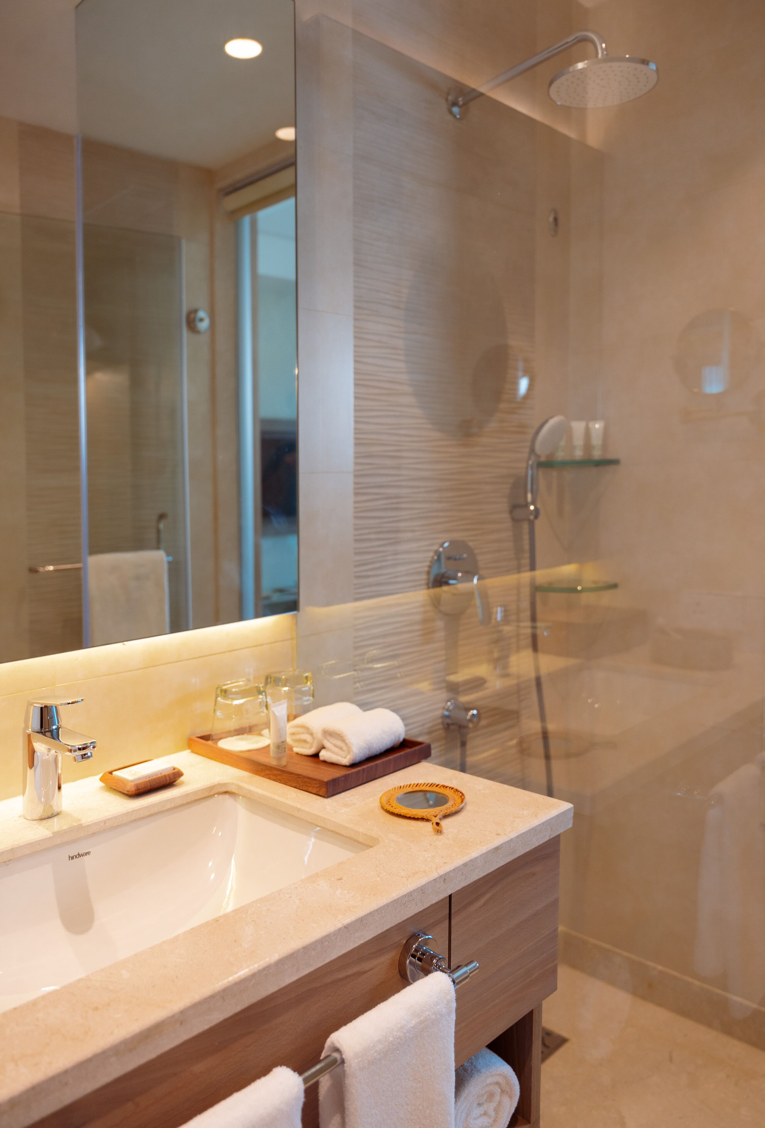 Une salle de bain moderne avec un grand miroir, un lavabo, une douche et un meuble-lavabo doté d’un porte-serviettes.