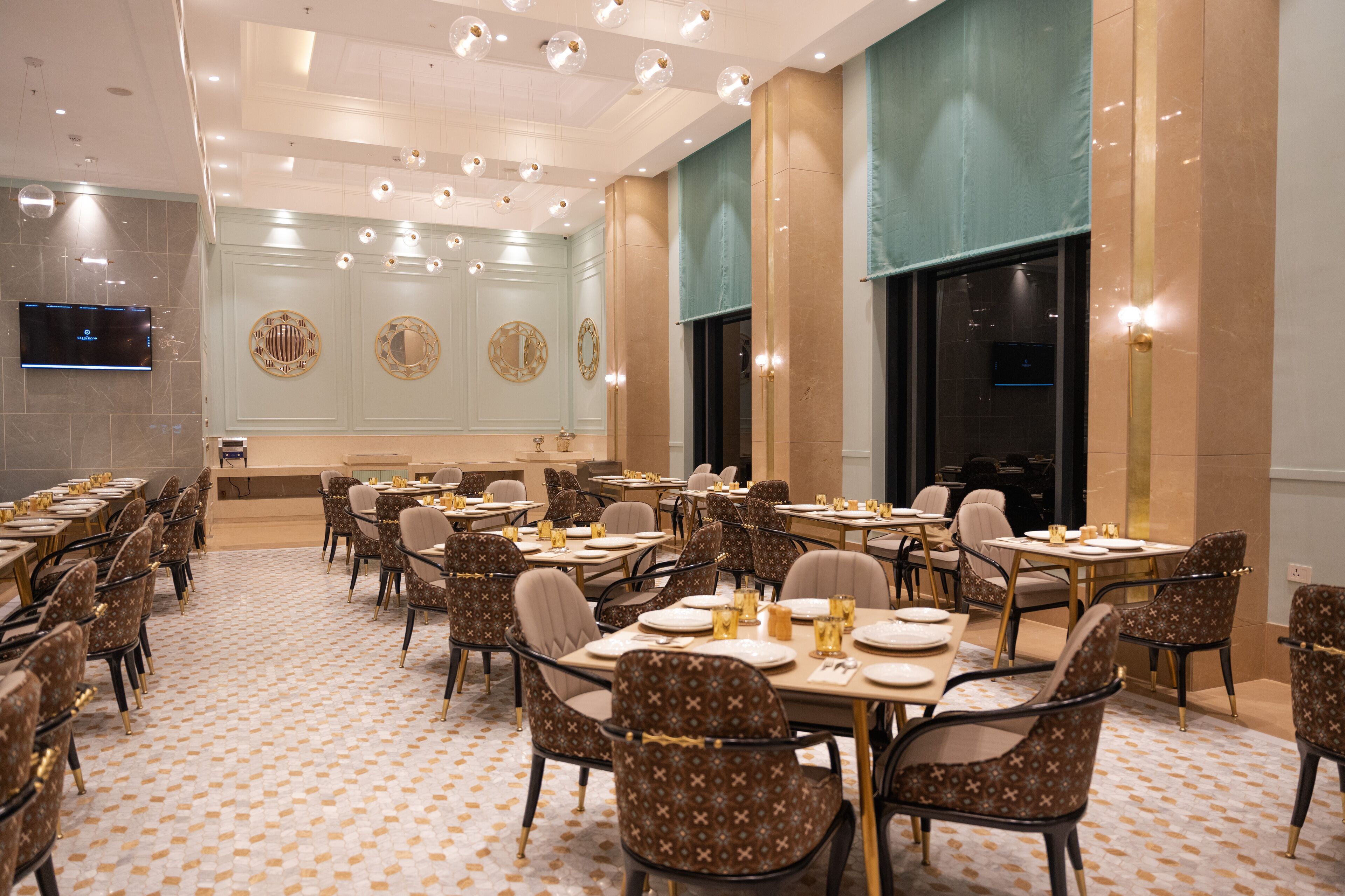 Un grand espace dédié à la salle à manger, avec plusieurs tables et chaises, un téléviseur fixé au mur et des miroirs décoratifs.