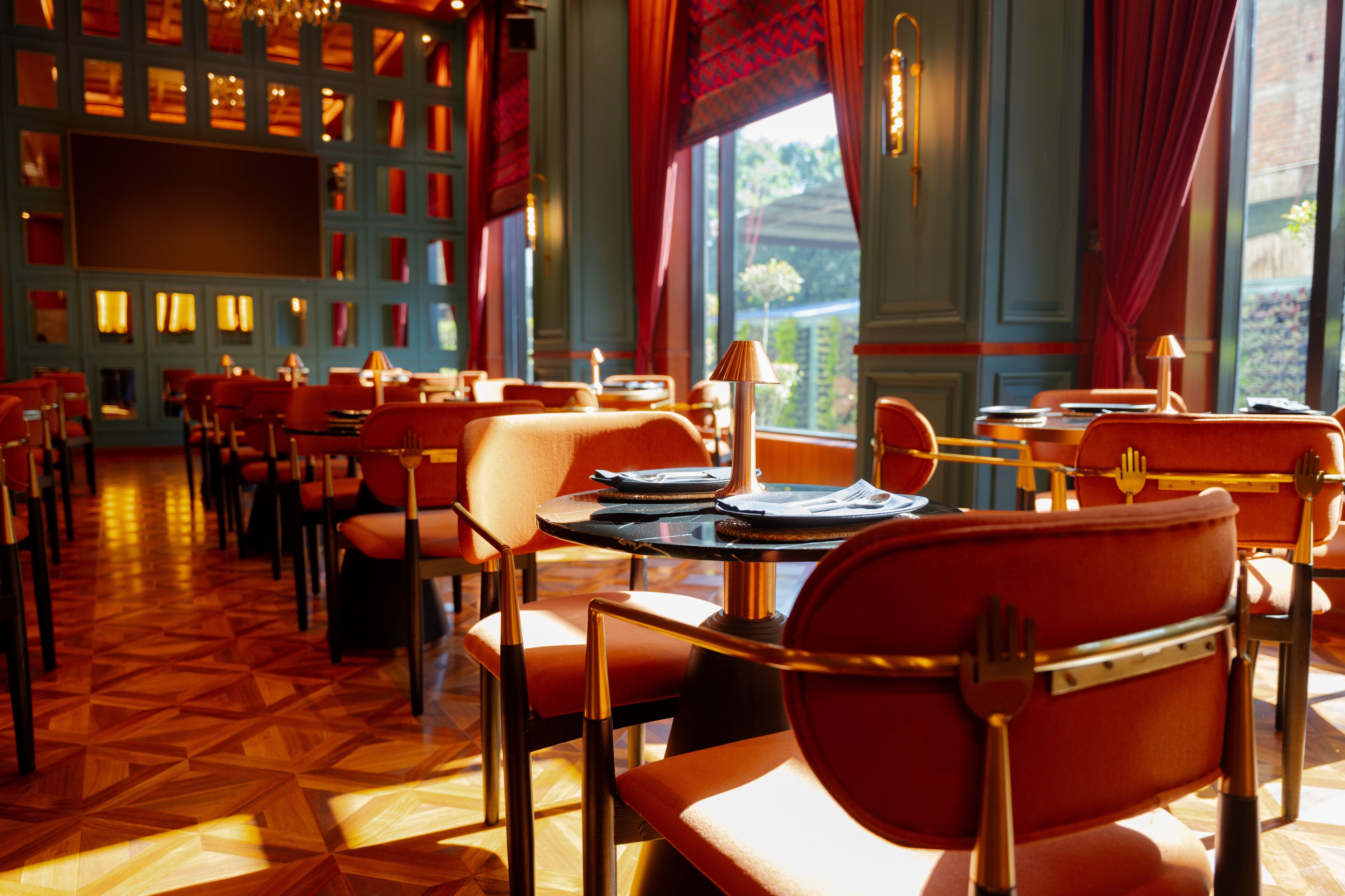 A restaurant with red upholstered chairs, round tables, and a patterned floor.
