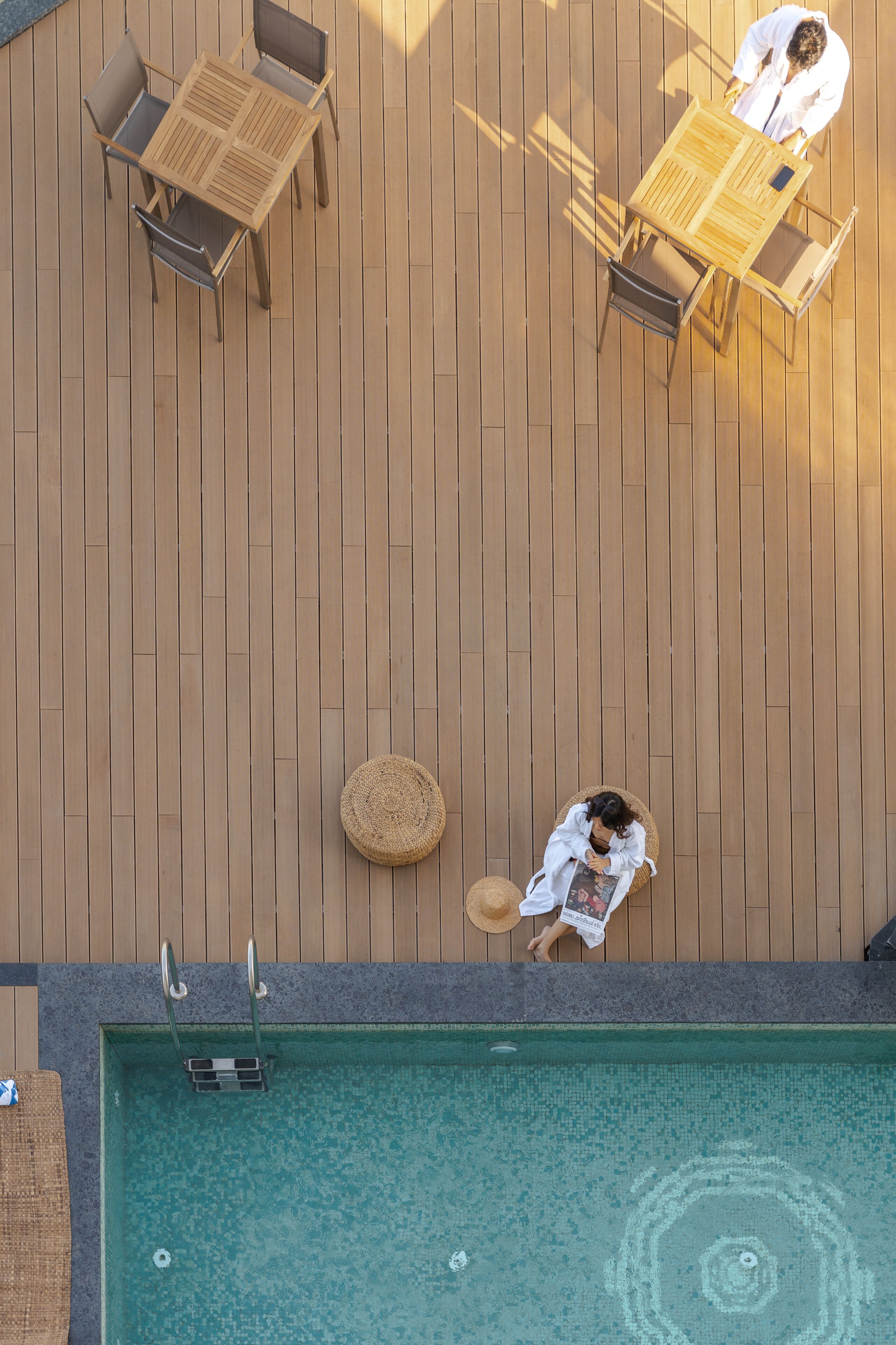 An outdoor wooden deck with a pool, lounge chairs, and a table.