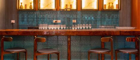 A bar area with a wooden counter and three bar stools.