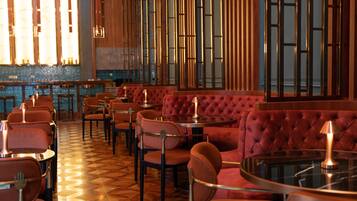 A restaurant interior with red upholstered booths, round tables, and a patterned floor.