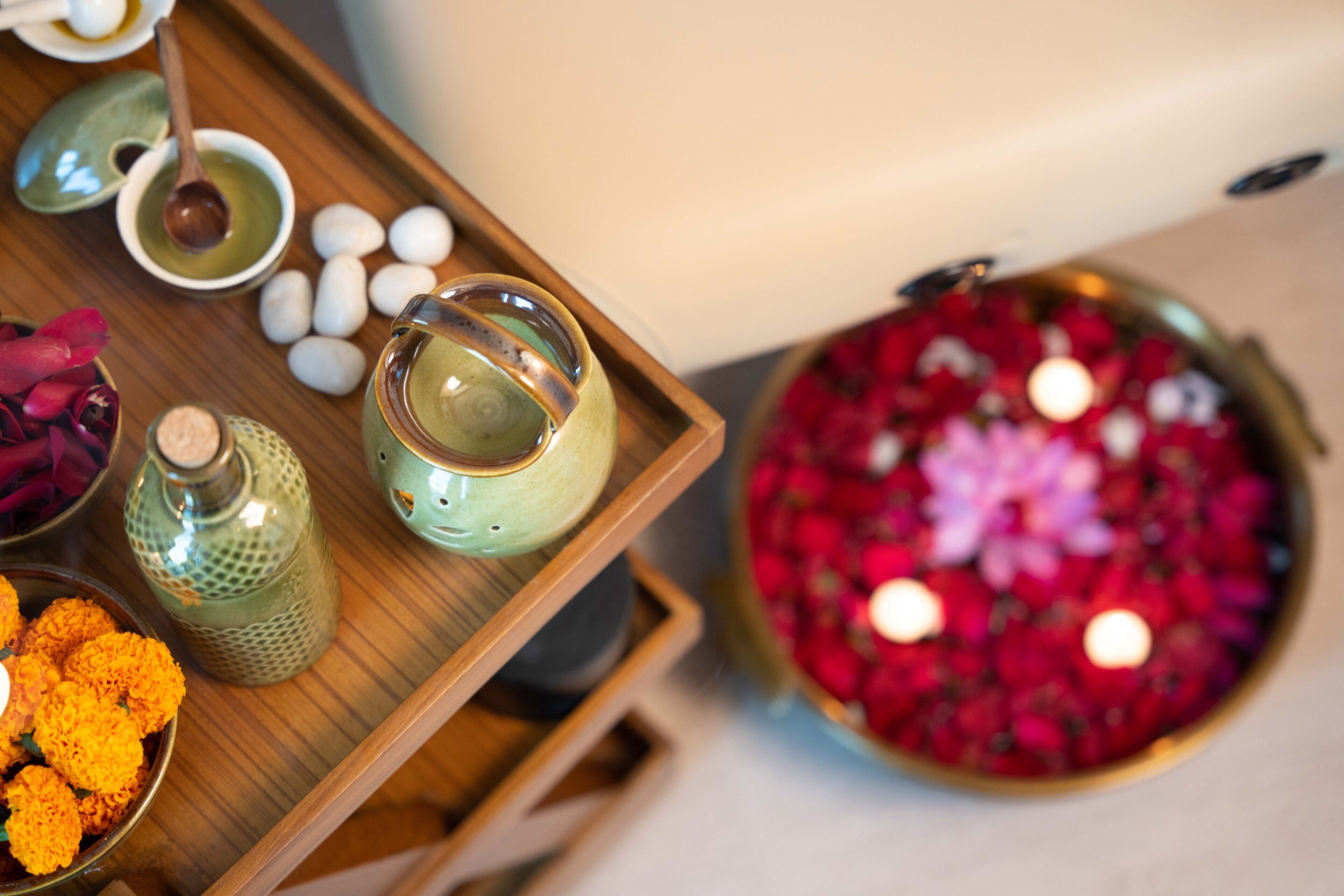 A tray with various items including a teapot, a bowl of marigold flowers, and a decorative bowl with red flowers.