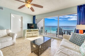 Relax in this stylish living room with a flat-screen TV, comfortable sofa, and sliding glass door leading to a balcony with ocean views.