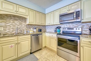 Fully equipped kitchen with stainless steel appliances, dishwasher, microwave, and oven.
