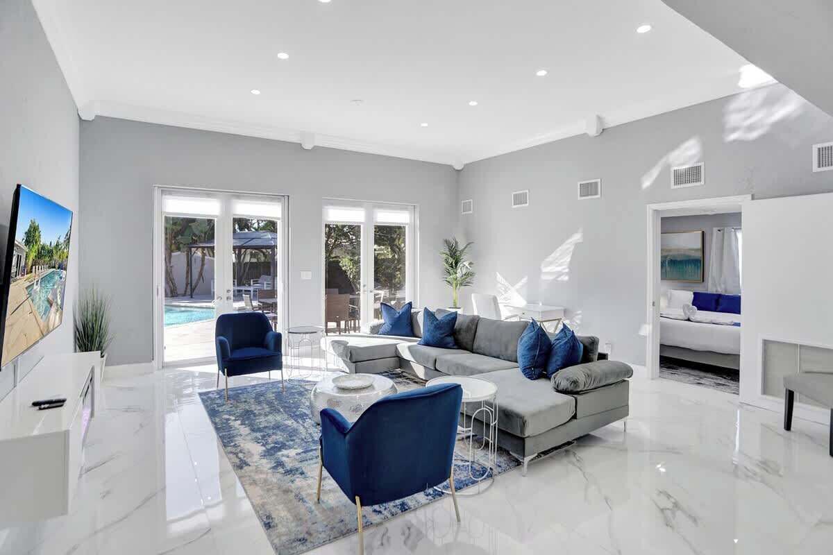 Un salon moderne avec un canapé gris, des fauteuils bleus et une table basse.