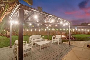 An outdoor patio with a covered seating area, a fire pit, and a wooden deck. - Resort Villa 6 BR Hted Pool Beach Volleyball (Lighthouse Point)
