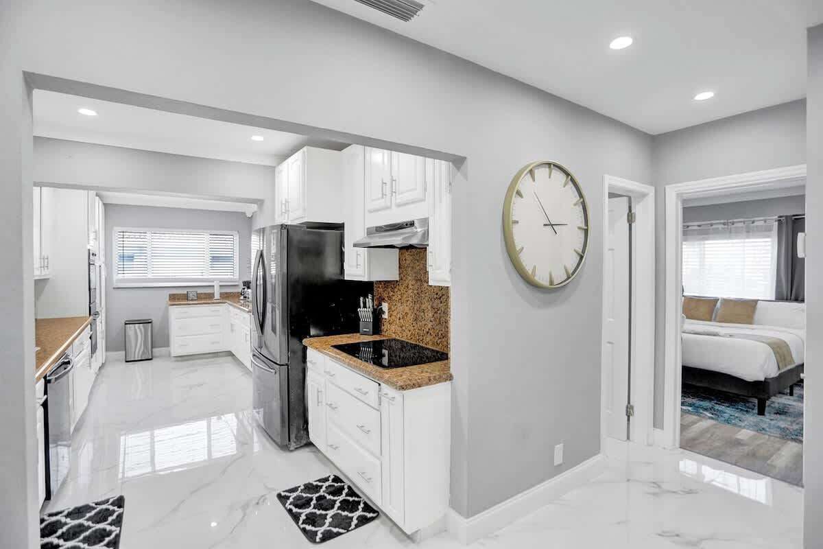 A modern kitchen with white cabinetry, a black refrigerator, and a granite countertop.