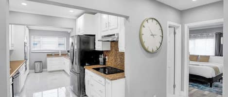 Una cocina moderna con armarios blancos, un refrigerador negro y una encimera de granito.