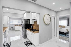 A modern kitchen with white cabinetry, a black refrigerator, and a granite countertop. - Resort Villa 6 BR Hted Pool Beach Volleyball (Lighthouse Point)