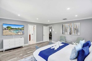 Une chambre d’hôtel avec un grand lit, un téléviseur à écran plat, un bureau et un tableau au mur.