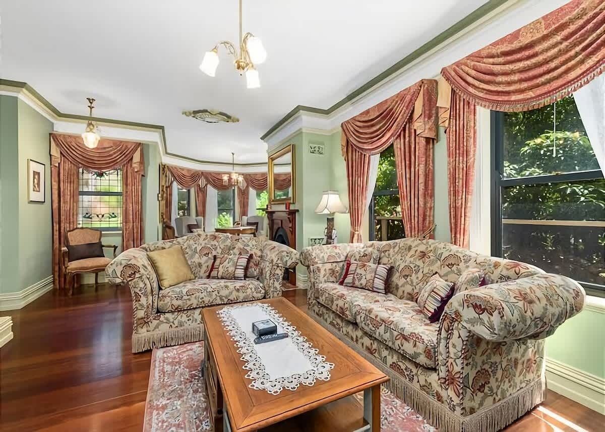 A room with a patterned sofa set, a wooden coffee table, and a chandelier.