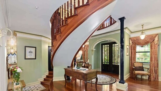 A grand staircase leading to a living area with a round table, a chair, and a door in the background. - The Castle Lilli Pilli Beach (LILLI PILLI)