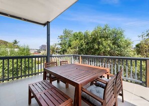 A wooden table and chairs on a balcony with a view of greenery and buildings. - Mindil Arch  Walk to 3 Beaches & River (TOMAKIN)