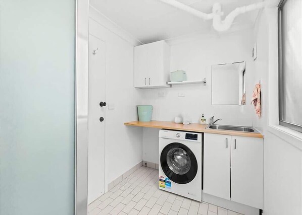 Una cocina compacta con lavadora, lavaplatos y ventana.
