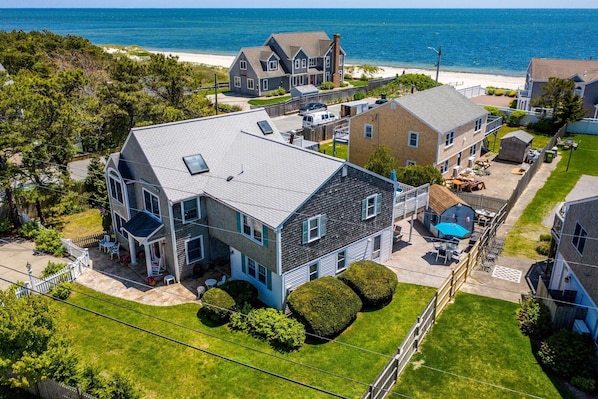 A residential area with houses, a swimming pool, and a beach in the background.