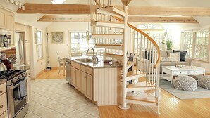 A spacious kitchen with a central island, a built-in stove, and a spiral staircase leading to an upper level. - 🌊 BEACHFRONT FAMILY HOME - 2026 Vrbo Rental Of The Year Award! (Yarmouth)