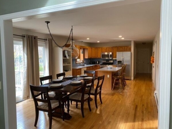 A spacious kitchen with wooden cabinets, a central island, and a dining area with a table and chairs.