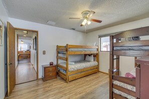 A bunk bed room with a ceiling fan, wooden flooring, and a small bedside table. - Ski, Hike & Fish: Big Bear Lake Home w/ Fire Pit (Big Bear Lake)