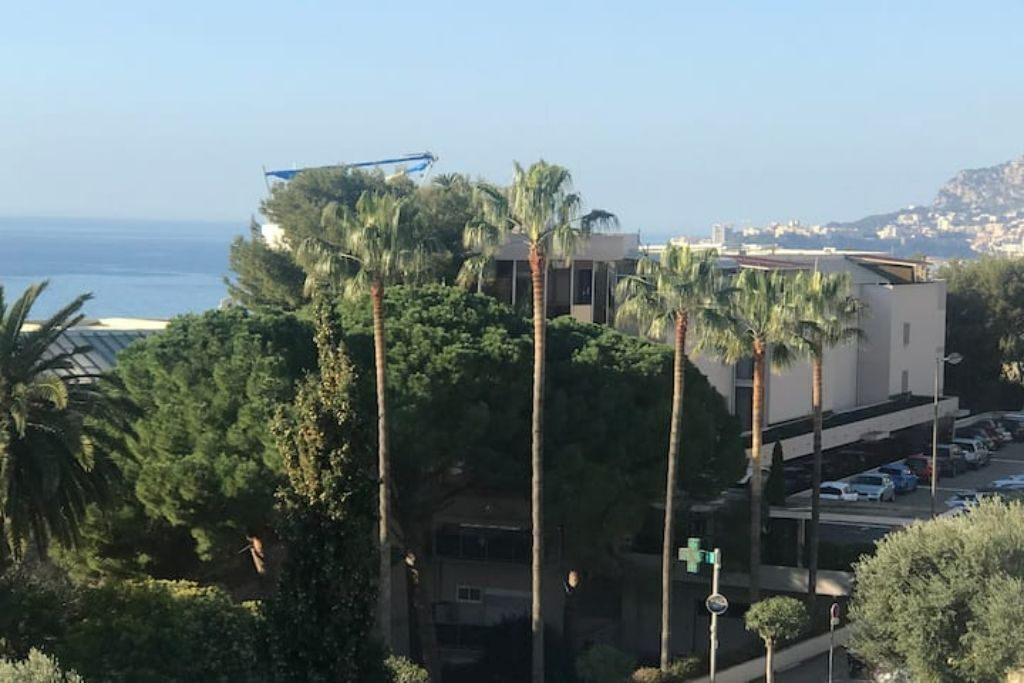 Ein Küstengebäude mit Palmen, einem Parkplatz und Blick auf das Meer.