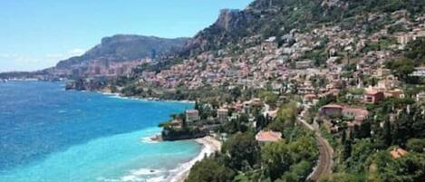 A coastal town with a beach, houses, and a mountain.