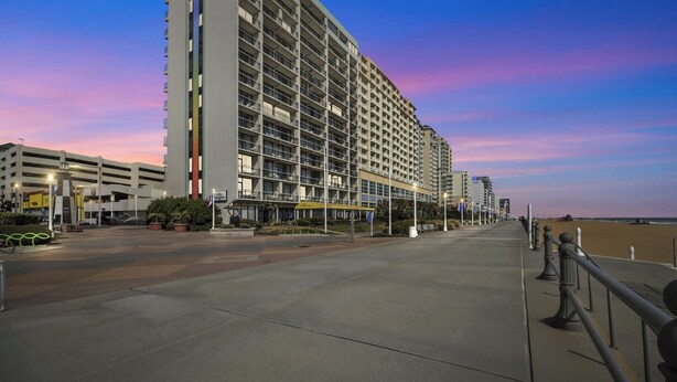 A high-rise hotel with multiple floors, a parking garage, and a beach view. - Four Sails Resort (Virginia Beach)