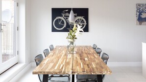 Un'area pranzo con un tavolo di legno, sedie, un vaso con fiori, un quadro a tema bicicletta e un quadro con la silhouette di un albero.