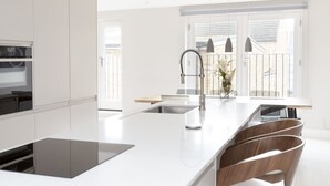 Una cucina moderna con una grande isola, mobili bianchi e vista all'esterno.