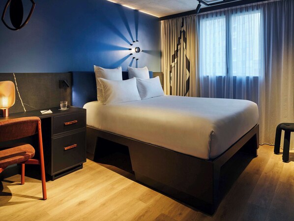 Relax in a spacious room with a large bed, modern desk, and comfortable chair.