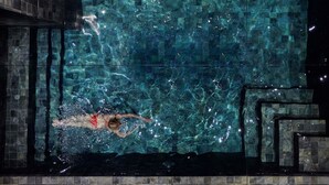 Ein Schwimmbecken mit klarem Wasser, eine Person schwimmt, und die Wände sind mit Fliesen versehen.